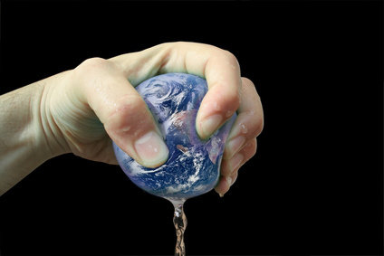 Main pressant la Terre de laquelle coule un liquide. Main pressant la Terre de laquelle coule un liquide