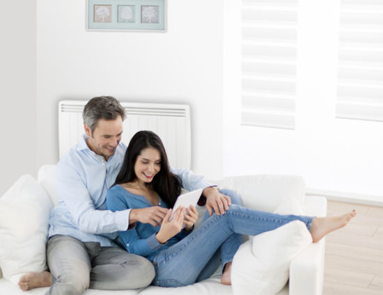 Couple sur un canapé devant un radiateur électrique.