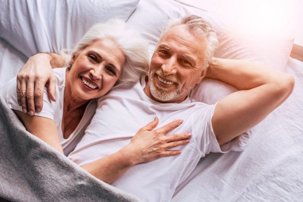 couple senior souriant dans un lit